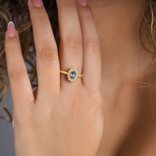 טבעת פרח מיוחד עם לונדון בלו טופז במרכז בחיתוך אובל עם יהלומים לבנים מסביב.jpg